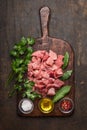 Raw ingredients for stew. pork meat cubes, oil ,salt and fresh seasoning on old rustic cutting board on dark wooden background top