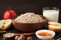 Raw ingrendients for healthy breakfast. Still life of oat flakes in the bowl, apple, milk, honey.