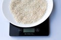 Raw italian rice in a white plate on a black weight scale on a white background. Royalty Free Stock Photo