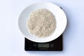 Raw italian rice in a white plate on a black weight scale on a white background. Royalty Free Stock Photo