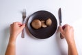 Raw Jersey cow mushrooms in a black plate and a knife and fork nearby on a white background top view. Human hands Royalty Free Stock Photo