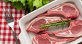 Raw Lamb Chops with Rosemary and Parsley in a White Dish on a Red and White Gingham Cloth Royalty Free Stock Photo