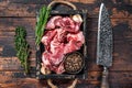 Raw lamb or goat meat diced for stew with bone. Dark wooden background. Top view