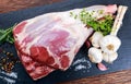 Raw lamb leg on blue stone background with herbs Royalty Free Stock Photo