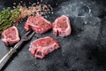 Raw lamb loin steaks, chops cutlets on kitchen table. Black background. Top view. Copy space