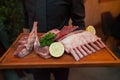 Raw lamb meat on disc wooden holding on hands of waiter.