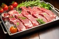 raw lamb rack on steel tray with scattered herbs Royalty Free Stock Photo