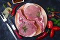 Raw Lamb Ribs with tomatoes, chili and hearbs on rustic black background. Top View