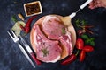 Raw Lamb Ribs with tomatoes, chili and hearbs on rustic black background. Top View