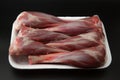 Raw lamb shanks in a white styrofoam box isolated on black background with copy space for text Royalty Free Stock Photo