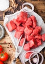 Raw lean diced casserole beef pork steak on chopping board with vintage fork on wooden background. Salt and pepper with fresh