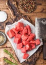 Raw lean diced casserole beef pork steak on chopping board with vintage meat hatchets on wooden background. Salt and pepper with
