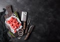 Raw lean diced casserole beef pork steak with vintage meat hatchet and fork with knife on stone background. Rosemary with red