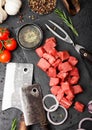 Raw lean diced casserole beef pork steak with vintage meat hatchet and fork on stone background. Salt and pepper with fresh