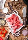 Raw lean diced casserole beef pork steak with vintage meat hatchet and knife and fork on wooden background. Salt and pepper with