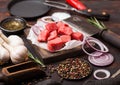 Raw lean diced casserole beef pork steak with vintage meat hatchet and knife and fork on wooden background. Salt and pepper with