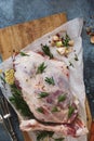 Raw leg of lamb studded with rosemary on baking parchment
