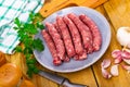 Raw longaniza sausages on plate with knife, garlic, peppercorns and parsley