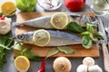 Fish with tomato, Basil, spices and lemon slices, chili peppers, mushrooms, oil, knife, fork, garlic, onion, on the kitchen