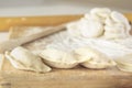 Raw manti, dumplings or dough wontons stuffed with minced meat on the kitchen table with flour on the background of a wooden Royalty Free Stock Photo