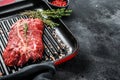 Raw marbled beef steak on a grill pan. Black background. Top view. Copy space Royalty Free Stock Photo