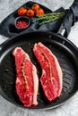 Raw marbled beef steak on a grill pan, ingredients for cooking. Gray background. Top view Royalty Free Stock Photo