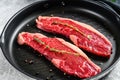 Raw marbled beef steak on a grill pan, ingredients for cooking. Gray background. Top view Royalty Free Stock Photo