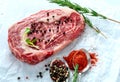 Raw marbled beef steak ribeye with spices, salt and pepper on white Kraft paper. Royalty Free Stock Photo