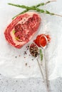 Raw marbled beef steak ribeye with spices, salt and pepper on white Kraft paper. Royalty Free Stock Photo