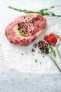 Raw marbled beef steak ribeye with spices, salt and pepper on white Kraft paper. Royalty Free Stock Photo