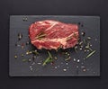 Raw marbled beef steaks with spices on a black cutting board on a black background. Top view with copy space Royalty Free Stock Photo