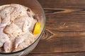 Quails marinated in spices with lemon in a glass saucepan on a wooden background. Close-up. Royalty Free Stock Photo