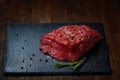 Raw meat beef steaks on black slate board with spices and rosemary over wooden background, copy space Royalty Free Stock Photo