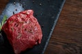 Raw meat beef steaks on black slate board with spices and rosemary over wooden background, copy space Royalty Free Stock Photo