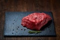 Raw meat beef steaks on black slate board with spices and rosemary over wooden background, copy space Royalty Free Stock Photo