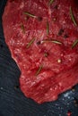 Raw meat beef steaks on black slate board with spices and rosemary over wooden background, copy space Royalty Free Stock Photo