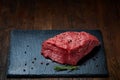 Raw meat beef steaks on black slate board with spices and rosemary over wooden background, copy space Royalty Free Stock Photo