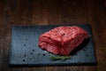 Raw meat beef steaks on black slate board with spices and rosemary over wooden background, copy space Royalty Free Stock Photo