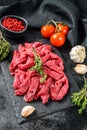 Raw meat cut into thin strips for beef Stroganoff. Black background. Top view