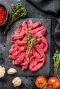 Raw meat cut into thin strips for beef Stroganoff. Black background. Top view Royalty Free Stock Photo