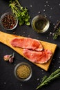 Raw meat on a cutting board. Dark background. Preparation for cooking pork meat. Various spices, seasonings lie nearby Royalty Free Stock Photo