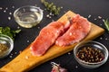 Raw meat on a cutting board. Dark background. Preparation for cooking pork meat. Various spices, seasonings lie nearby Royalty Free Stock Photo