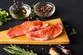 Raw meat on a cutting board. Dark background. Preparation for cooking pork meat. Various spices, seasonings lie nearby Royalty Free Stock Photo