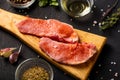 Raw meat on a cutting board. Dark background. Preparation for cooking pork meat. Various spices, seasonings lie nearby Royalty Free Stock Photo