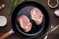 Raw meat on frying pan on wooden background with herbs and spices. Royalty Free Stock Photo