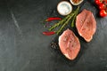 Raw meat, pork steaks with spices, herbs on board on dakr table background. Copy space, top view Royalty Free Stock Photo