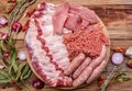 Raw meat products.Barbecue pork ribs, steaks, grilled sausages,minced meat, garnished with spices on a round wooden chopping board Royalty Free Stock Photo