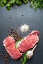 Raw meat salt and spices. Top view of fresh slices of raw meat, garlic, rosemary and spices on black slate stone plate. Preparing Royalty Free Stock Photo