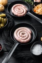 Raw meat sausage in cast iron frying pan  on black wooden table background Royalty Free Stock Photo