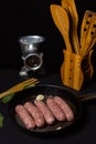 Raw meat sausages in a frying pan on a black background. Royalty Free Stock Photo